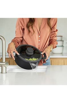 a woman is washing vegetables in a pot