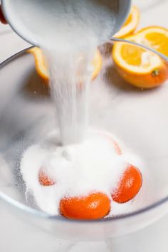 oranges being washed in a bowl with sugar