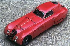 a red sports car sitting on top of a cobblestone road