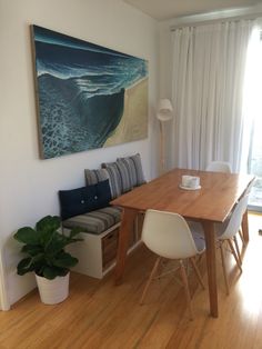 a wooden table sitting in front of a window next to a white chair and potted plant