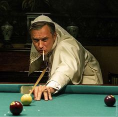 a man leaning over a pool table with a cue in his mouth and two balls on it