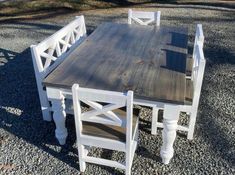 a table and chairs made out of wood sitting next to each other on gravel ground