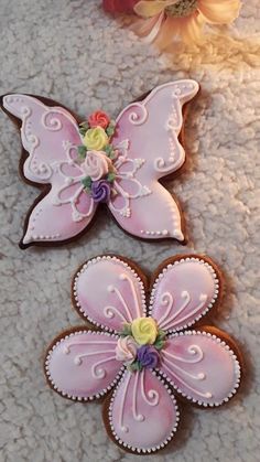 two decorated cookies sitting on top of a white carpet next to flowers and a vase