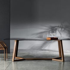 a table with two wine glasses on it and a chair next to it in front of a wall