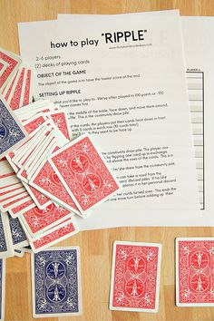 a pile of playing cards sitting on top of a wooden table next to a piece of paper