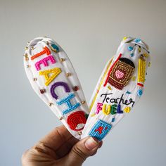 two handmade bookmarks with the words teacher and student written on them are held in front of a white wall