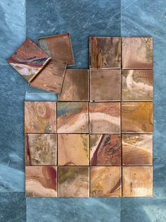 several square pieces of metal sitting on top of a blue tablecloth covered in brown and gold foil