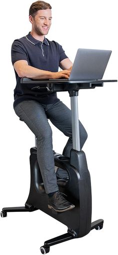 a man sitting at a desk with a laptop on his lap top and legs crossed