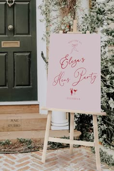 a pink sign sitting on top of a wooden easel in front of a door