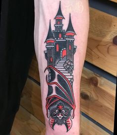 a tattoo on the arm of a person with a bat and castle in the background