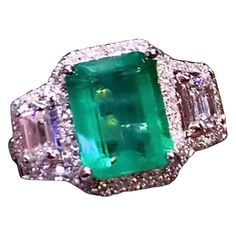 An exquisite Art Deco design, so gorgeous and chic, a very glamour ring handmade, in 18k gold with a natural Zambia emerald of 3,43 carats, fine quality, and 2 pieces of emerald cut diamonds and round brilliant cut diamonds of 1,04 carats, F/VS( top quality). Handcrafted by artisan goldsmith. Excellent manufacture and quality. Complete with AIG report. Whosale price. Note: on my shipment, customers NOT PAY TAXES and DUTY. Luxury Emerald Ring With 17 Jewels For Promise, Luxury Emerald Birthstone Ring For Promise, Luxury Emerald Birthstone Promise Ring, Exquisite Emerald Cut Ring For Promise, Exquisite Emerald Cut Ring With Accent Stones, Exquisite Emerald Cut Emerald Ring, Exquisite Emerald Cut Emerald Ring With Accent Stones, Dazzling Green Diamond Ring With Brilliant Cut, Dazzling Green Promise Ring