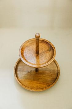 two wooden trays sitting on top of each other with one holding an object in the middle