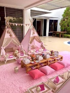 two teepee tents are set up with pink pillows