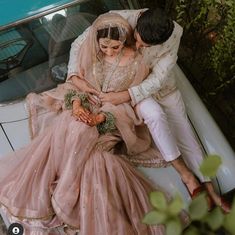 a bride and groom sitting on top of a car