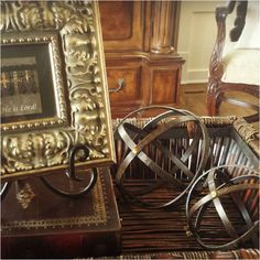 antique frames and other antiques are on display in a room with wood flooring, wicker furniture, and an ornate gold framed mirror