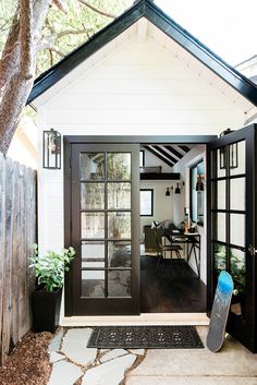 a black and white house with a skateboard on the front door, next to a tree