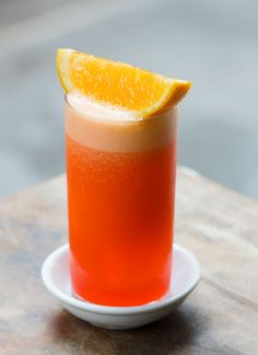 an orange slice on top of a drink in a white glass with a saucer