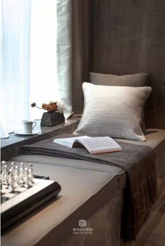 a bed sitting next to a window with a book on top of it