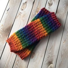 a multicolored crocheted mitt laying on top of a wooden floor