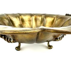 a large metal bowl with gold decoration on the rim and foot rests against a white background