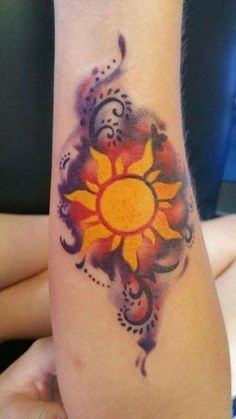 a woman's arm with an orange and yellow flower tattoo on her left arm