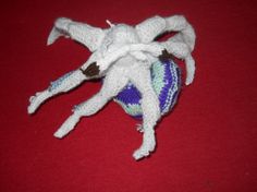 a crocheted spider laying on top of a red surface