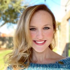 a woman with blonde hair and blue sweater smiling