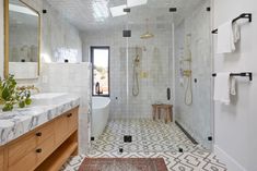 a bathroom with white tile and wooden cabinets, two sinks and a walk in shower