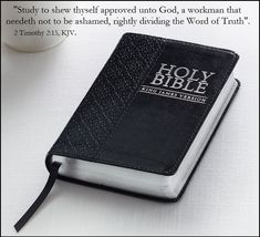 a black bible sitting on top of a white table next to a cup of coffee