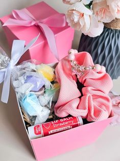 a pink box filled with lots of baby items next to a vase full of flowers