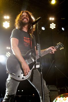 a man with long hair playing an electric guitar on stage