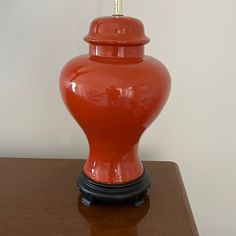 an orange vase sitting on top of a wooden table