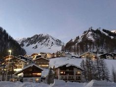 the mountains are covered in snow and lit up by street lights at night, with houses on either side