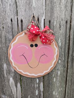 a wooden sign with a red bow on it's head hanging from a fence