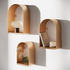 three shelves with vases and books on them against a white wall in the corner