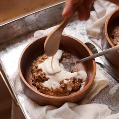 a person is spooning milk into a bowl of oatmeal