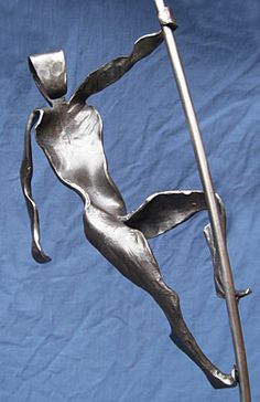 a metal sculpture of a woman holding a pole on a blue cloth covered background,