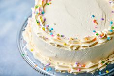 a cake with white frosting and sprinkles on a glass platter