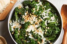 a bowl filled with greens and nuts next to bread