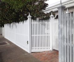 a white picket fence next to a tree