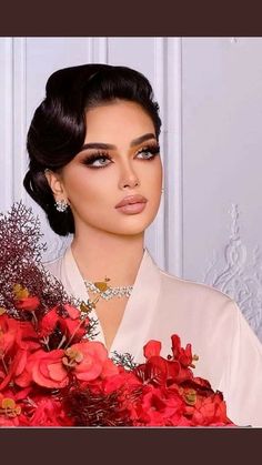 a woman holding a bouquet of red flowers in her right hand and looking at the camera