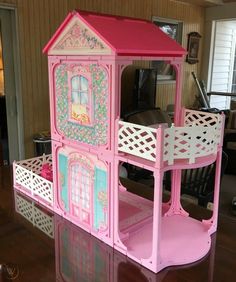 a pink doll house sitting on top of a wooden table