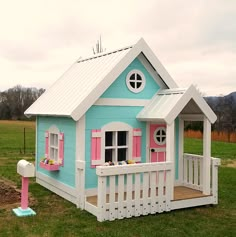 a small blue and white house with pink shutters