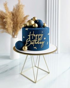 a blue birthday cake with gold decorations on top