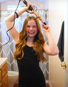 a woman is blow drying her hair in the bathroom