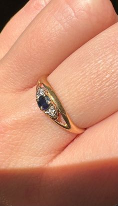 a woman's hand with a gold ring and blue sapphires on it,