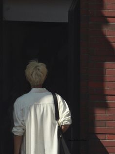 a person with blond hair is standing in the doorway and holding onto a black bag