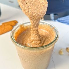 a spoon full of peanut butter on top of a jar