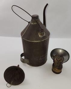 an old metal jug and other items on a white surface