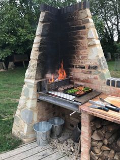 an outdoor bbq grill with food cooking on it's sides and fire in the middle